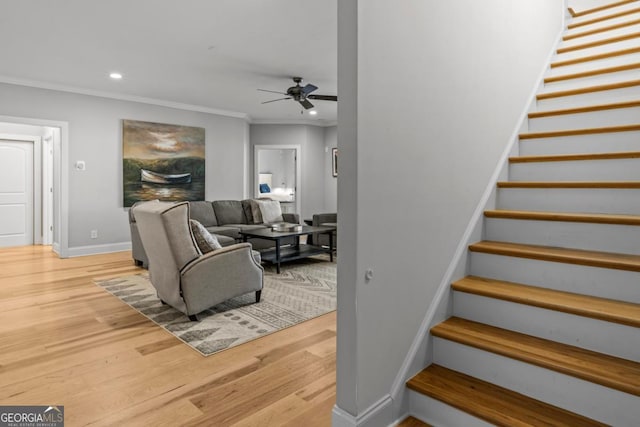 stairway with crown molding, ceiling fan, and wood-type flooring