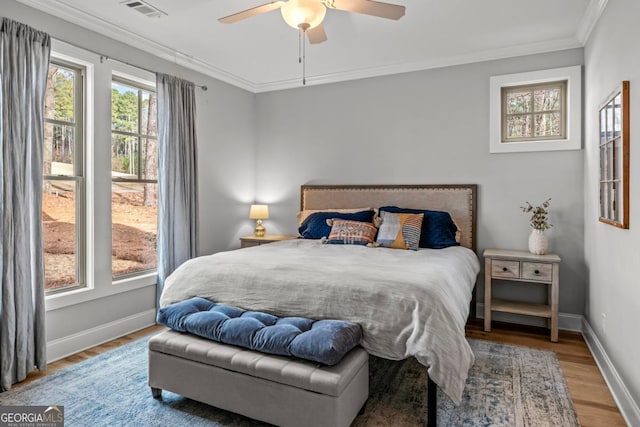 bedroom with hardwood / wood-style flooring, ornamental molding, and ceiling fan