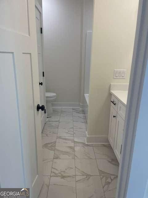 bathroom featuring vanity, a washtub, and toilet