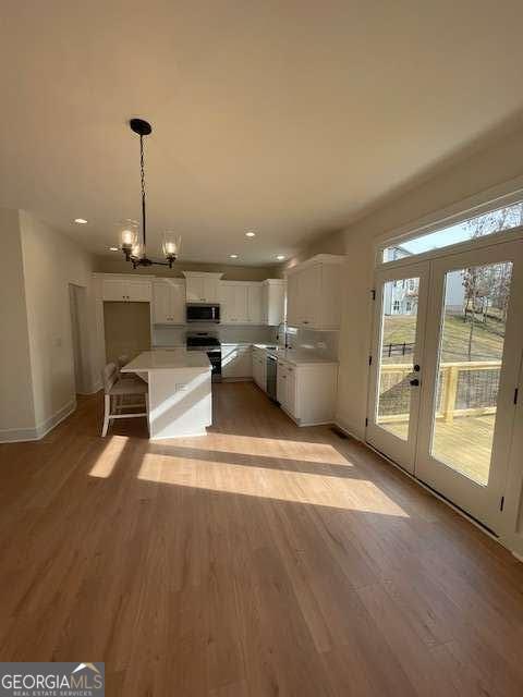 kitchen featuring white cabinetry, hanging light fixtures, light hardwood / wood-style flooring, and appliances with stainless steel finishes