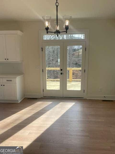 entryway with a notable chandelier, light hardwood / wood-style floors, and french doors