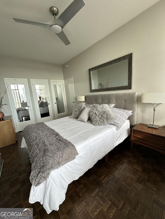 bedroom featuring ceiling fan, dark parquet flooring, and a textured ceiling