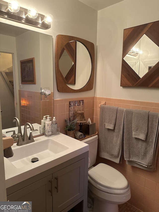 bathroom with tile walls, vanity, and toilet