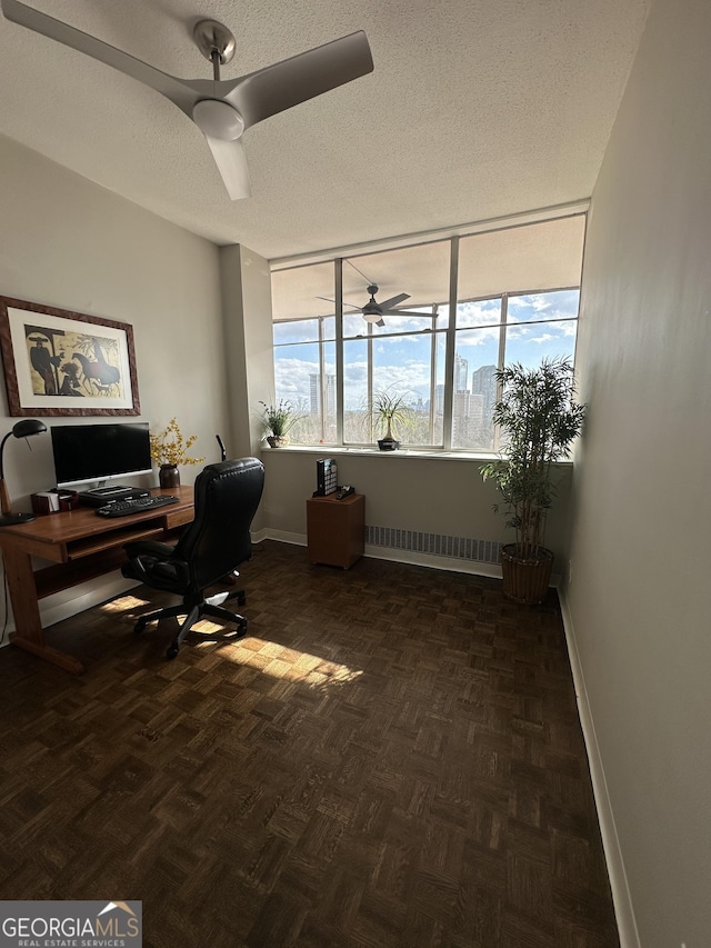 office area featuring ceiling fan, dark parquet flooring, a textured ceiling, and radiator heating unit