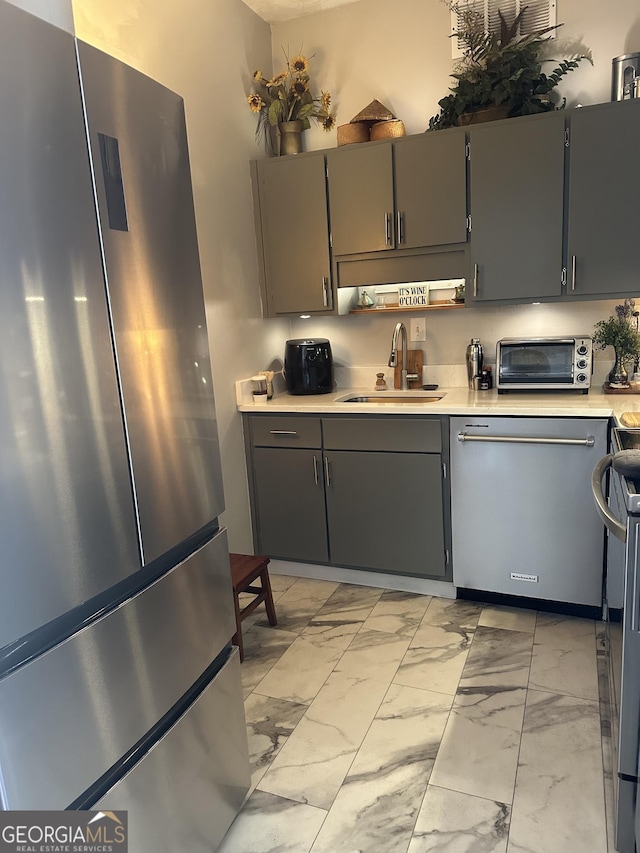 kitchen with appliances with stainless steel finishes, sink, and gray cabinetry