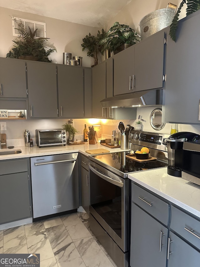 kitchen with gray cabinetry, sink, light stone counters, and stainless steel appliances