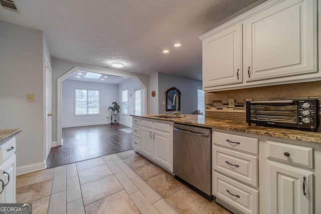 kitchen with dishwasher, sink, white cabinets, and backsplash