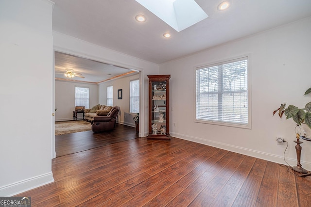 living area featuring a skylight, ornamental molding, and dark hardwood / wood-style floors