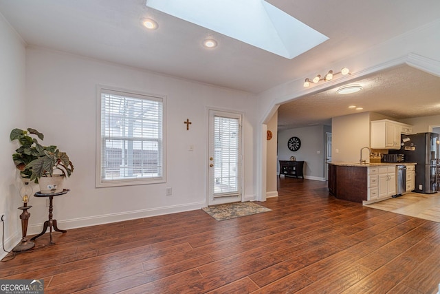 entryway with ornamental molding, dark hardwood / wood-style floors, and a skylight