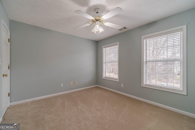 carpeted spare room with a textured ceiling and ceiling fan