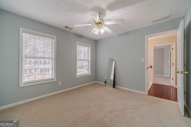 unfurnished room featuring ceiling fan, light carpet, and a textured ceiling