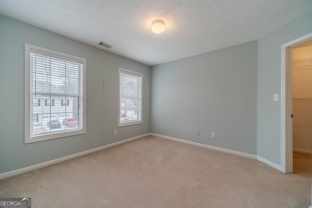 empty room featuring light colored carpet and a textured ceiling