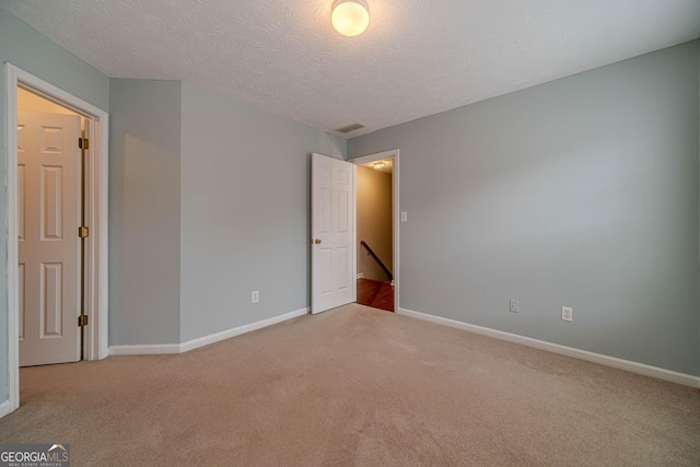 carpeted spare room with a textured ceiling