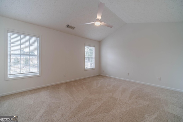 carpeted spare room with ceiling fan, lofted ceiling, and a textured ceiling