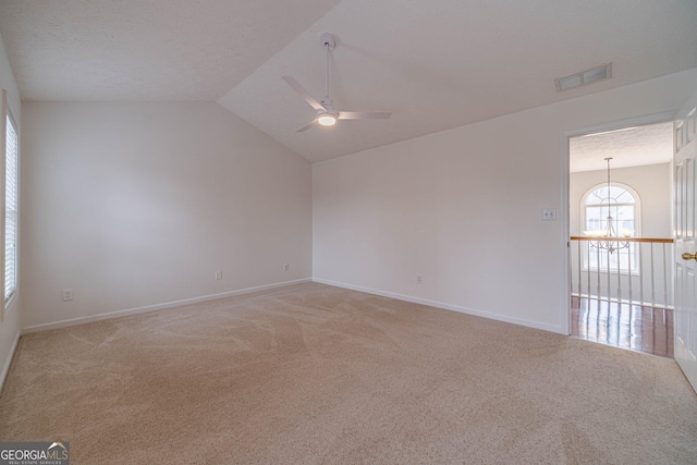 unfurnished room with ceiling fan with notable chandelier, vaulted ceiling, a textured ceiling, and carpet flooring