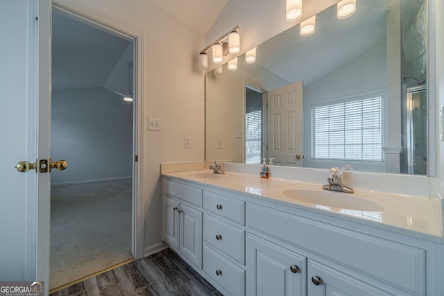 bathroom with vanity, hardwood / wood-style flooring, vaulted ceiling, and a shower with door