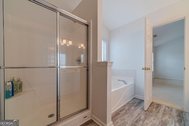 bathroom with hardwood / wood-style flooring, vaulted ceiling, and separate shower and tub