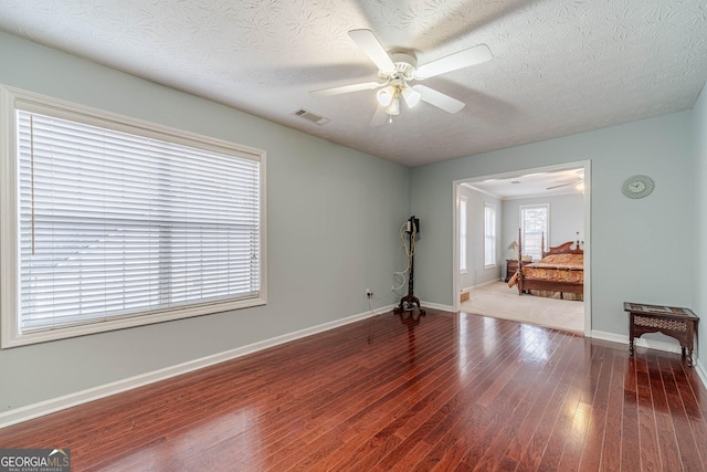 empty room with hardwood / wood-style flooring, a textured ceiling, and ceiling fan