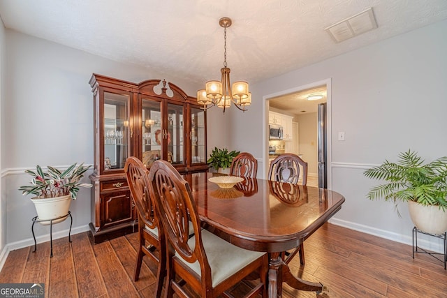 dining room with a chandelier, a textured ceiling, and dark hardwood / wood-style flooring