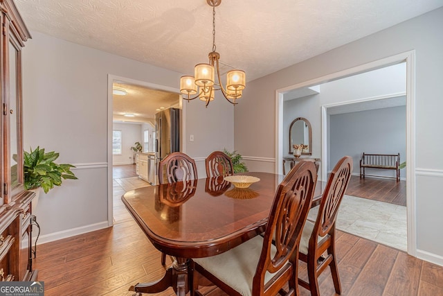 dining room with a notable chandelier, light hardwood / wood-style flooring, and a textured ceiling