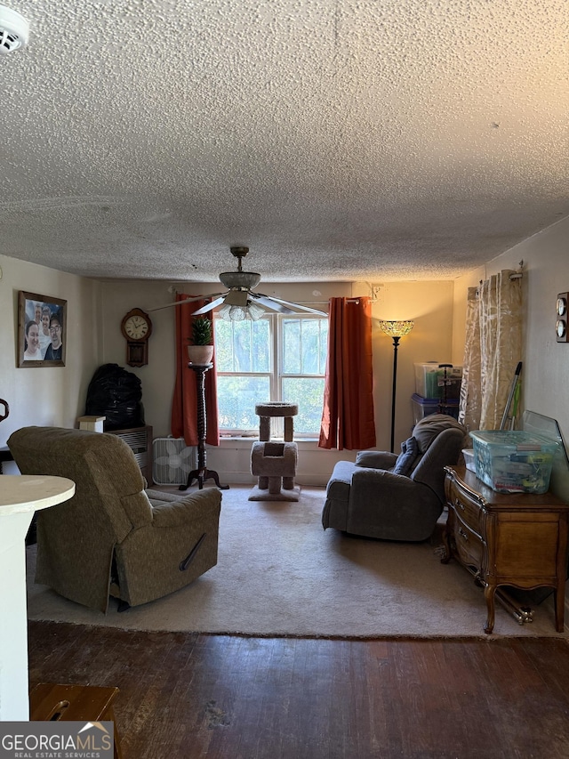 living room with a textured ceiling, wood-type flooring, and ceiling fan