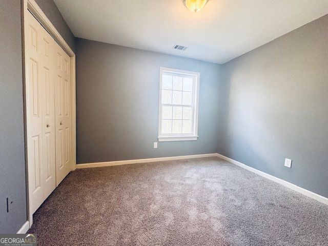 unfurnished bedroom featuring dark carpet and a closet