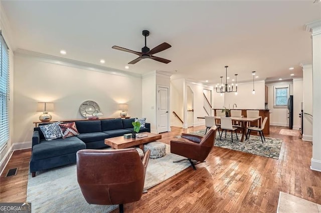 living room featuring crown molding, ceiling fan with notable chandelier, and light hardwood / wood-style floors