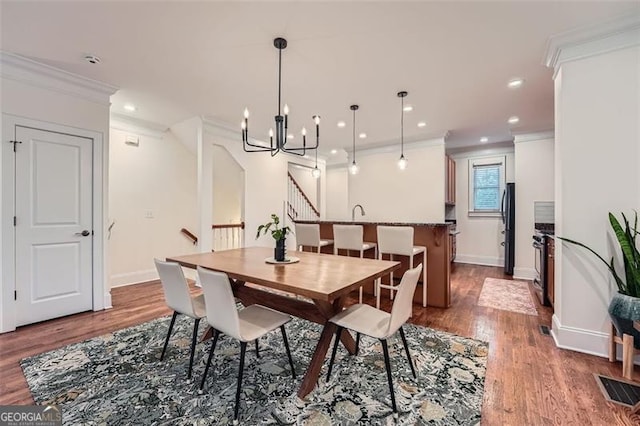 dining area with hardwood / wood-style flooring, ornamental molding, and a chandelier