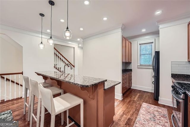 kitchen with pendant lighting, crown molding, dark stone countertops, and black fridge