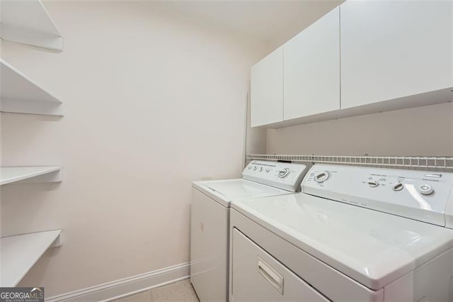 clothes washing area featuring cabinets and separate washer and dryer