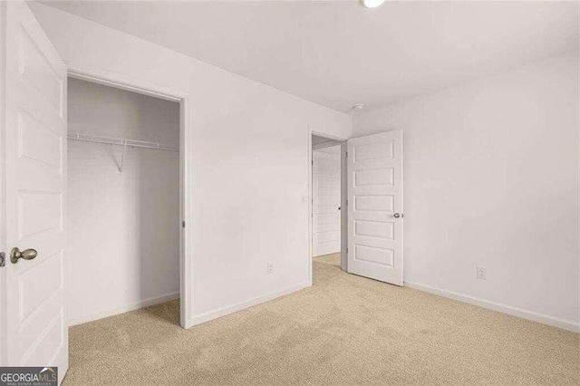 unfurnished bedroom featuring light colored carpet and a closet