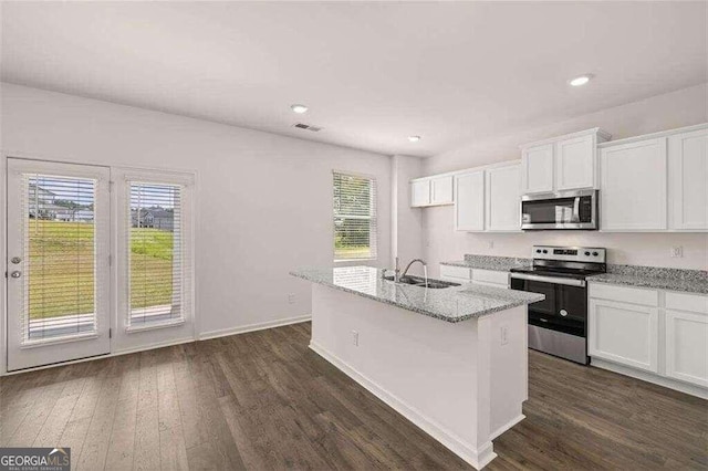 kitchen featuring appliances with stainless steel finishes, white cabinetry, a kitchen island with sink, light stone counters, and dark hardwood / wood-style flooring