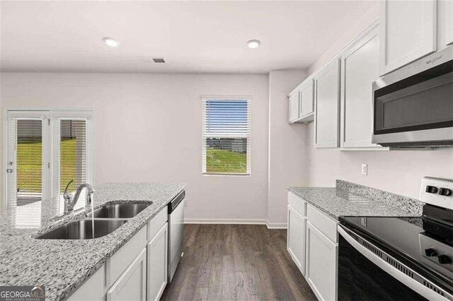 kitchen featuring appliances with stainless steel finishes, sink, white cabinets, light stone countertops, and dark wood-type flooring