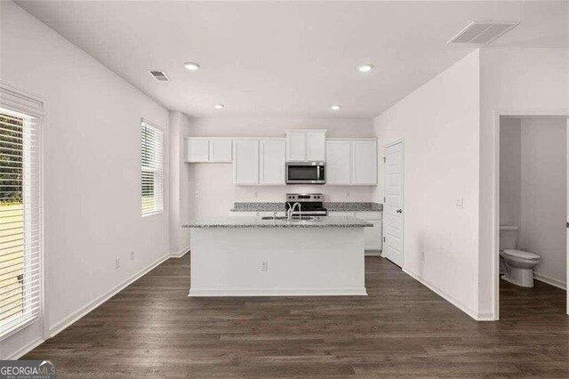 kitchen featuring sink, white cabinetry, light stone counters, a center island with sink, and appliances with stainless steel finishes