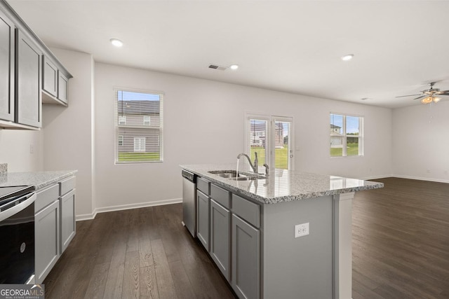 kitchen with an island with sink, gray cabinets, sink, and light stone countertops