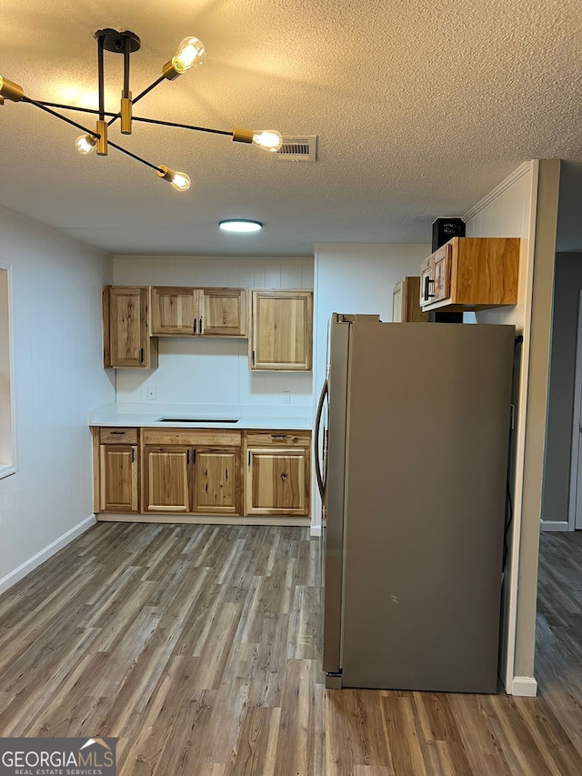 kitchen featuring hardwood / wood-style floors, a textured ceiling, and stainless steel refrigerator