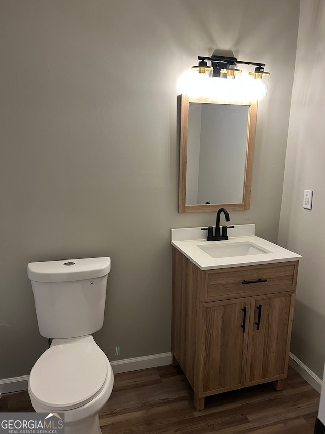 bathroom with hardwood / wood-style flooring, vanity, and toilet