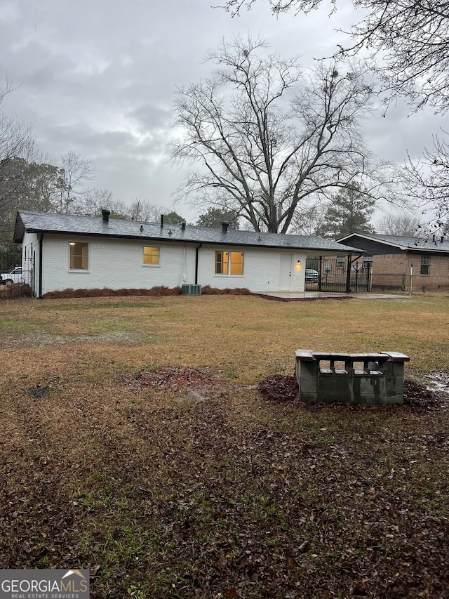 rear view of house featuring cooling unit and a lawn