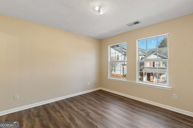 spare room featuring dark wood-type flooring and a textured ceiling