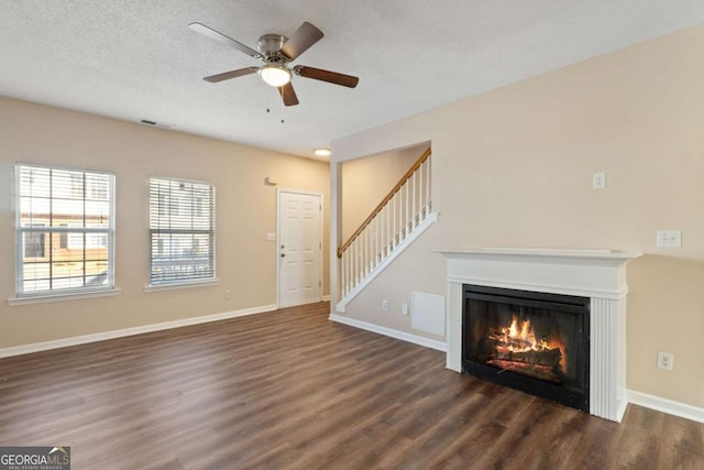 unfurnished living room featuring dark hardwood / wood-style flooring, ceiling fan, and a textured ceiling