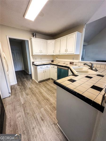 kitchen featuring tile countertops, sink, white refrigerator, stainless steel dishwasher, and kitchen peninsula