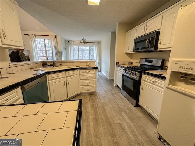 kitchen featuring dishwasher, sink, white cabinets, tile counters, and stainless steel range with gas stovetop