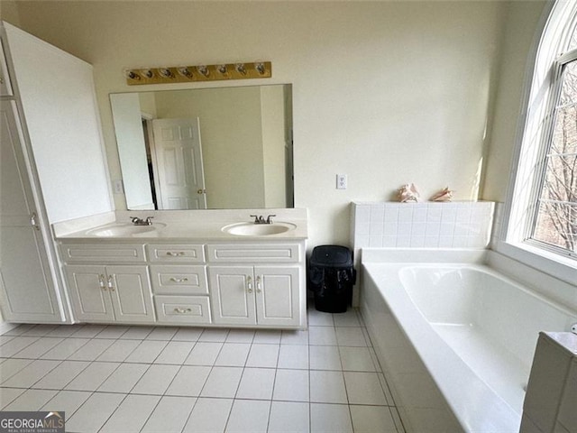 bathroom with a relaxing tiled tub, vanity, and tile patterned floors