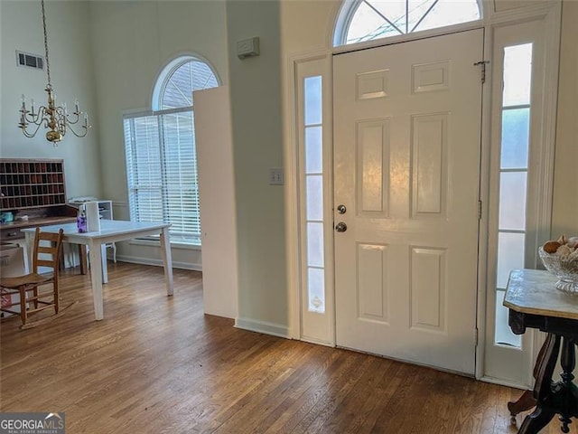 foyer entrance featuring plenty of natural light, dark hardwood / wood-style floors, and an inviting chandelier