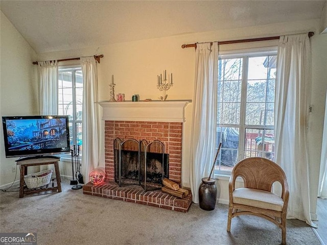 sitting room with a fireplace, vaulted ceiling, carpet, and a textured ceiling