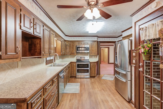 kitchen with ornamental molding, stainless steel appliances, light hardwood / wood-style floors, and sink