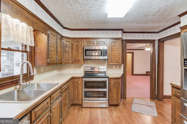 kitchen with stainless steel appliances, ornamental molding, sink, and light hardwood / wood-style floors