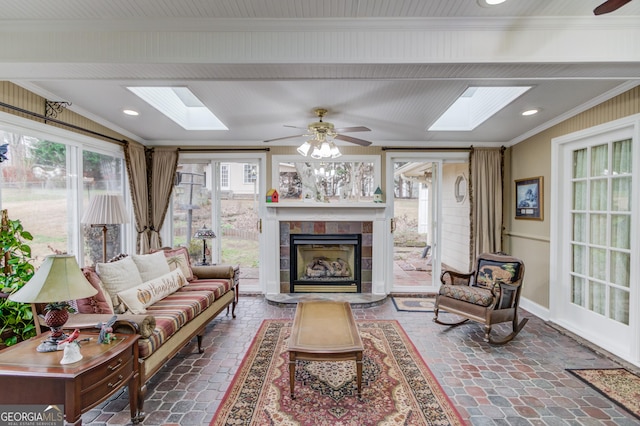 sunroom with ceiling fan, a skylight, and a tile fireplace