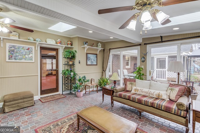 living room with crown molding, a skylight, and ceiling fan