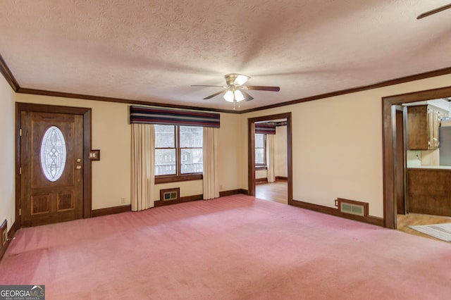 carpeted foyer entrance featuring ceiling fan, ornamental molding, and a textured ceiling